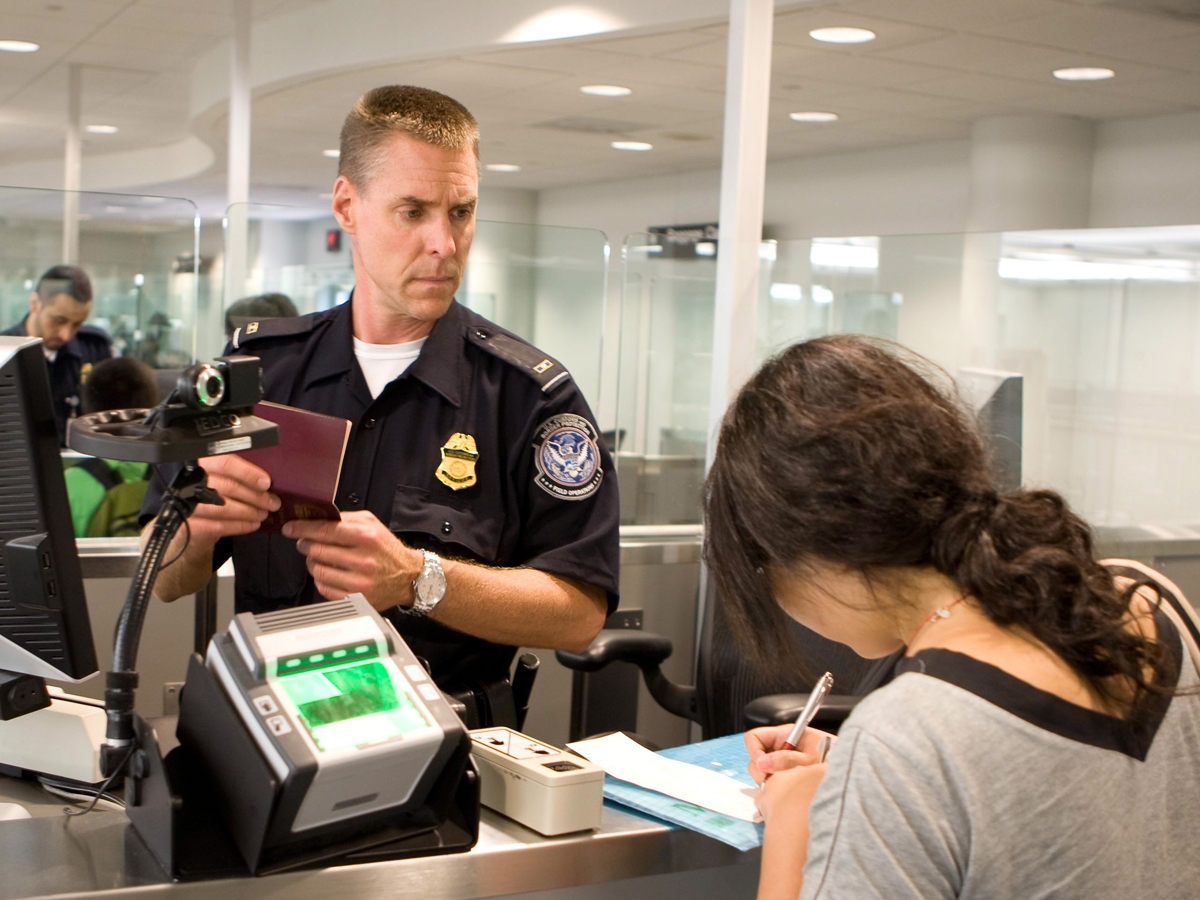 A CBP officer processing an international passenger at an airport inspection station