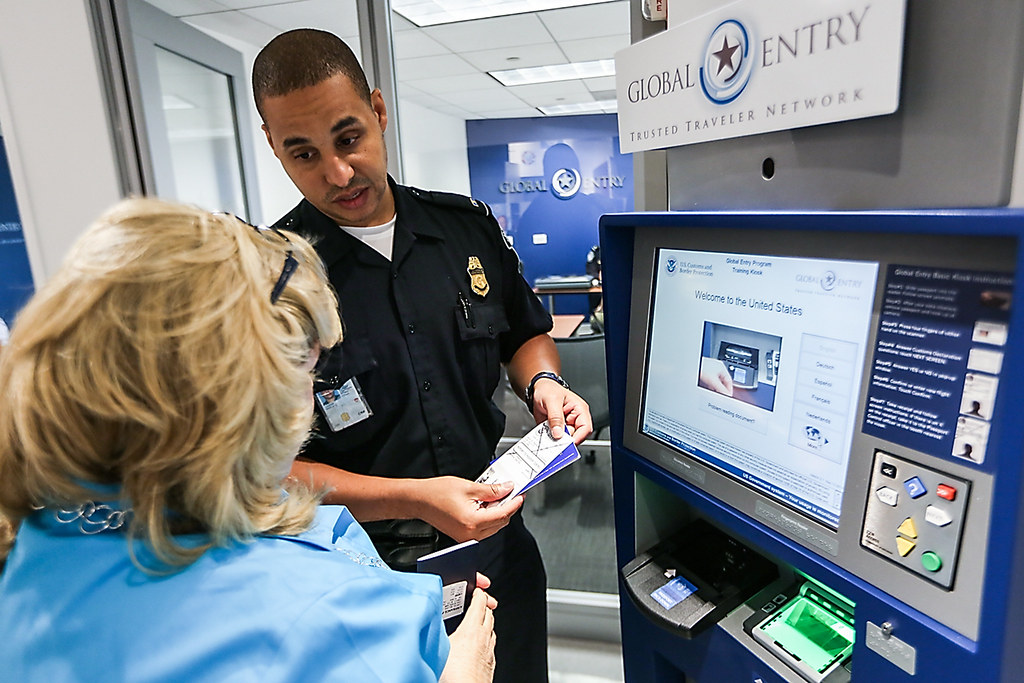 CBP officer showing a traveler how to use a Global Entry kiosk at an enrollment center
